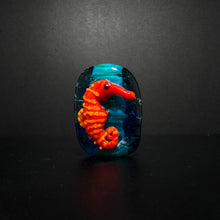 Red and Orange Sea Horse Bead on an Ocean Themed Back Ground.